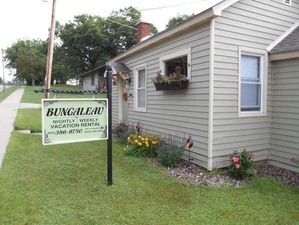 A bungalow with a sign advertising nightly and weekly vacation rental.