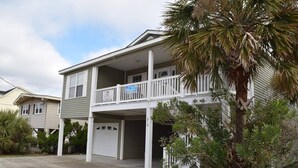 A two-story house with a balcony, a garage, and a palm tree in the foreground. - Clean Beach House on 2nd row easy access to beach! (Cherry Grove)