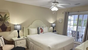 A bedroom with a large bed, two bedside tables with lamps, a chair, and a window with a view of the outdoors. - Clean Beach House on 2nd row easy access to beach! (Cherry Grove)
