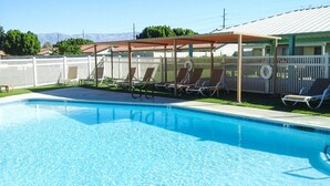 Une piscine avec des chaises longues et un espace de repos abrité.