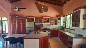 A spacious kitchen with a central island, wooden cabinets, and a dining area with chairs. - Spectacular views in very private and exquisitely landscaped setting (Atenas)