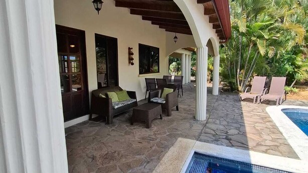 A covered outdoor seating area with stone flooring, a pool, and tropical vegetation. - Spectacular views in very private and exquisitely landscaped setting (Atenas)