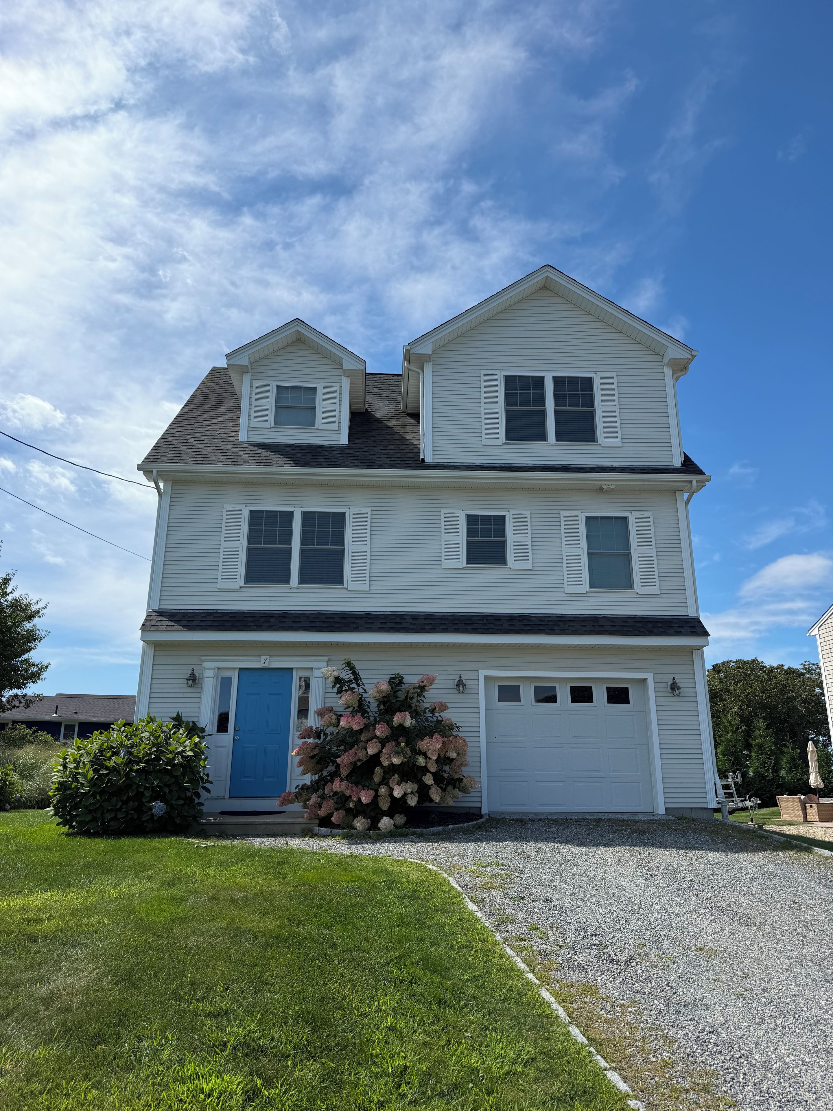 A two-story house with a blue door, a garage, and a driveway.