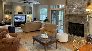 Un salón espacioso con chimenea, asientos cómodos y televisor.