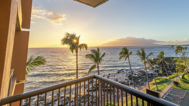 A balcony with a view of the ocean and palm trees. - Beachfront Mana Kai Maui Unit #502 (Kihei)