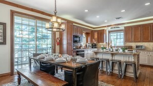 A spacious kitchen with wooden cabinets, a central island with stools, and a dining table set for six.