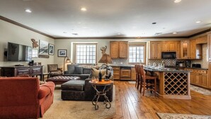 A spacious living room with a fireplace, a dining area, and a kitchen with wooden cabinets and a built-in island.