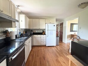 A kitchen with wooden cabinets, a black countertop, a white refrigerator, and a wooden dining table.