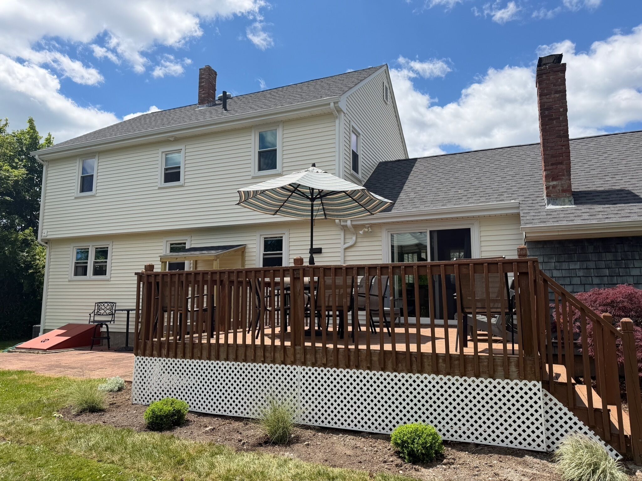 A two-story house with a deck, outdoor furniture, and a clear sky.