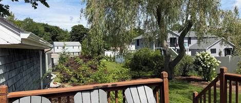 Eine Terrasse mit Adirondack-Stühlen, einem Holgitter und Blick auf eine Wohngegend mit Häusern und Bäumen.