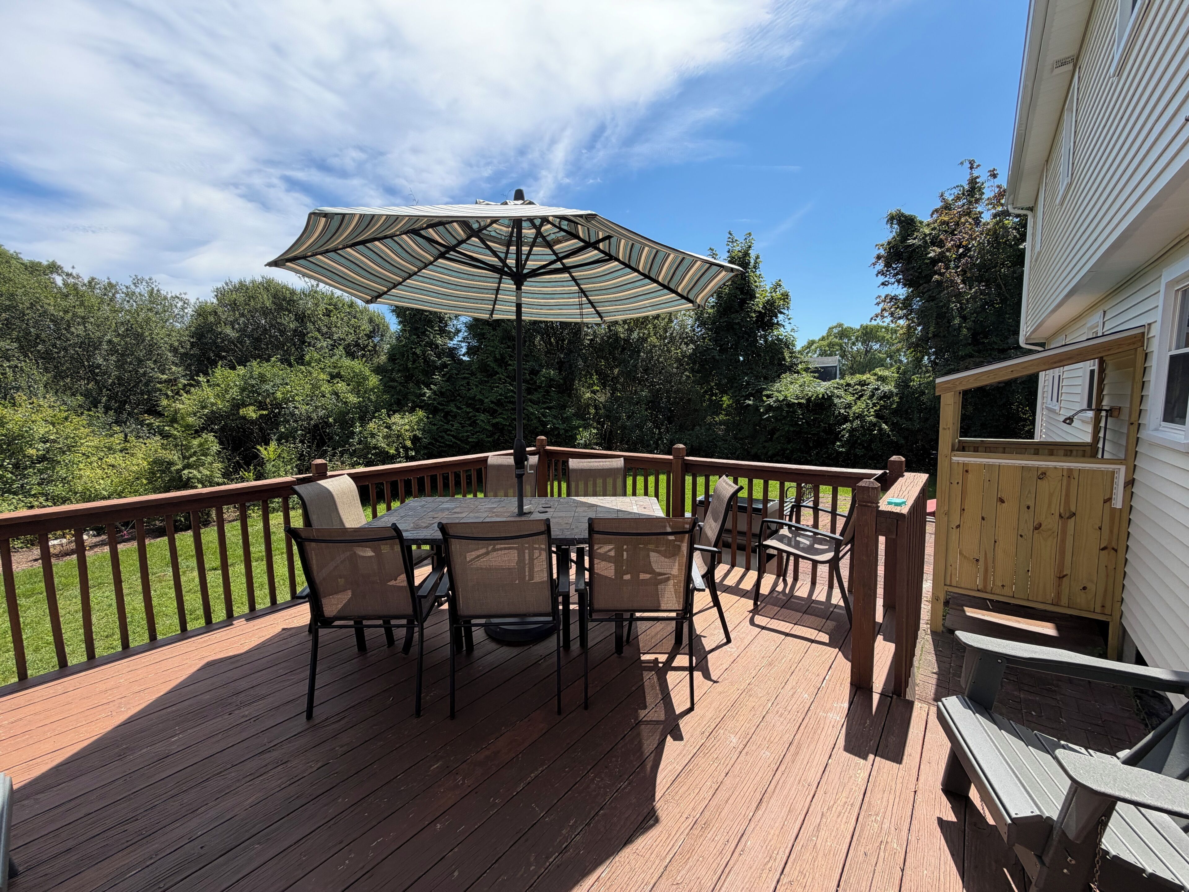 A deck with a table and chairs, an umbrella, and a wooden fence.