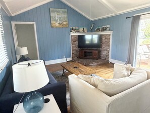 A living room with a TV, sofa, lamp, and artwork on the wall.