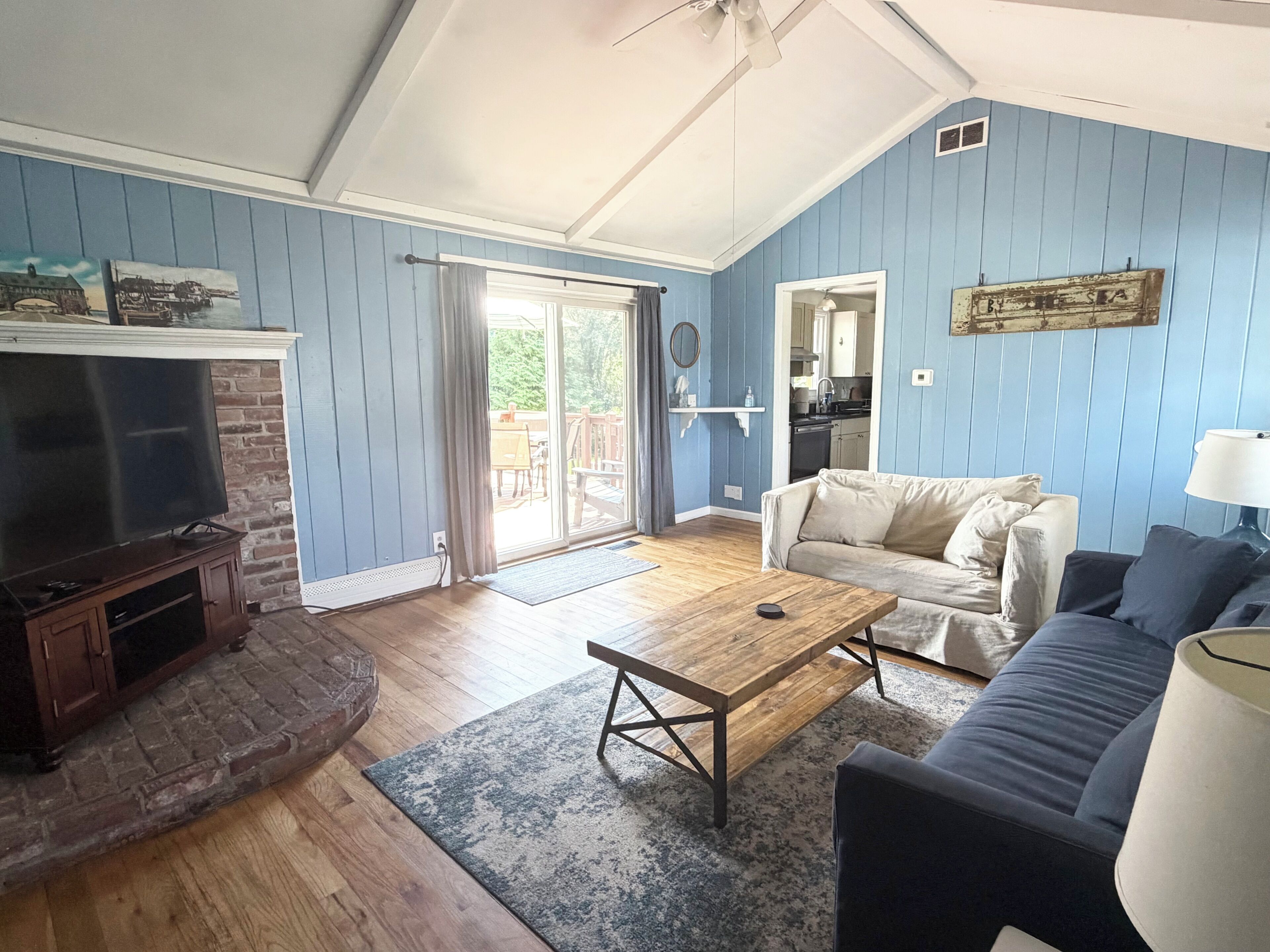 A living room with a television, sofa, coffee table, and a view to the outside.