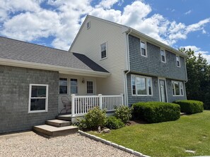 A two-story house with a front porch, a brick foundation, and a well-maintained lawn.