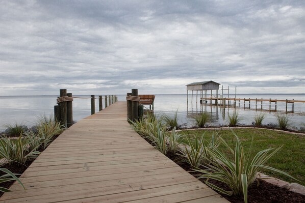 Un muelle de madera que conduce a una estructura cubierta junto al agua.