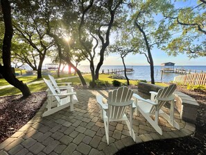 Un patio con sillas Adirondack que da a un cuerpo de agua y un muelle.