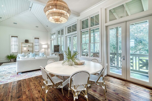 Relax in a spacious living area with a round table, wicker chairs, and a high ceiling with exposed beams.