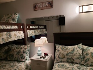 A bedroom with bunk beds, a bedside table with a lamp, and a mirror.