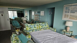 Une pièce comprenant un lit, deux canapés, un fauteuil et une table avec une lampe.