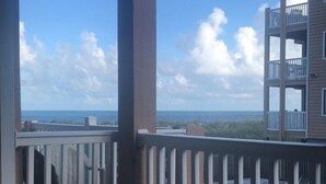 Ein überdachter Balkon mit Blick auf das Meer und ein Gebäude gegenüber.