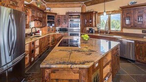 A spacious kitchen with wooden cabinets, a large island, stainless steel appliances, and a view of the outdoors.