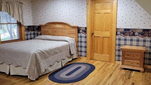 Ein Schlafzimmer mit einem hölzernen Bett, einem Nachttisch, einer Tür und einem Fenster mit Vorhängen.