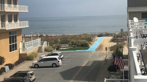 Et kysthotel med parkeringsplads og havudsigt, samt en blå sti ned til stranden.