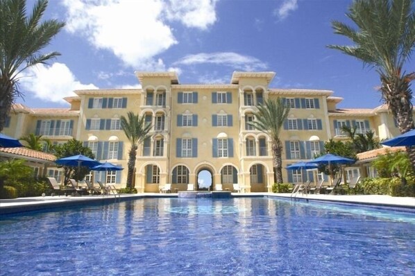 Experience the grandeur of this hotel's central arched entrance, surrounded by a tranquil pool and lush palm trees.