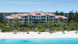 Un hôtel situé en bord de mer, doté de nombreux balcons, d’une piscine et de parasols de plage.