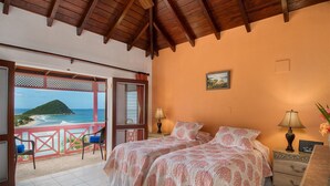 Une chambre avec deux lits, un balcon donnant sur la mer et un plafond en bois.