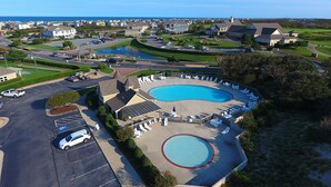 Zona residencial con una gran piscina rodeada de sillones de descanso y un estacionamiento.