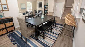 Un comedor con una mesa de madera oscura, sillas de mimbre y un tapete azul y blanco a rayas.