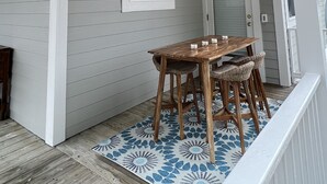 Un espacio al aire libre cubierto con una mesa y sillas de madera, luces colgantes y un tapete estampado.