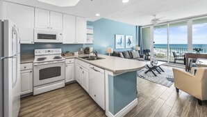 Een moderne keuken met witte kasten, een centraal eiland en uitzicht op de oceaan door grote ramen.