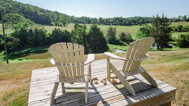 Two Adirondack chairs on a wooden deck overlooking a grassy landscape with trees and a hill in the distance. - Relax in the beautiful South River Valley just minutes from wineries,  (Stanardsville)