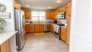 A modern kitchen with wooden cabinets, stainless steel appliances, and a yellow rug. - Relax in the beautiful South River Valley just minutes from wineries,  (Stanardsville)