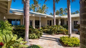 Un resort tropicale con una veranda coperta, palme e un vialetto in pietra.
