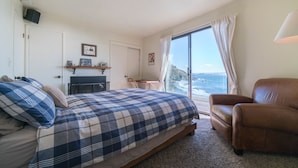 A bedroom with a bed, a chair, a desk, and a view of the ocean. - Ocean front property, minutes from San Francisco in the middle of National Park. (Muir Beach)