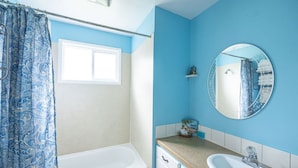 Un baño con bañera, lavabo y espejo.