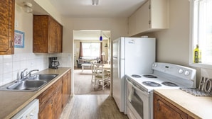 Una cocina compacta con armarios de madera, un refrigerador blanco, una estufa y un lavamanos.