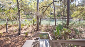 A wooden staircase leading to a deck overlooking a natural area with trees and a body of water. - Inlet Cove Paradise #36 (Kiawah Island)