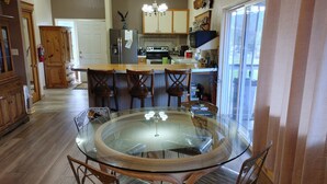 A modern kitchen with a glass dining table surrounded by wooden chairs, a built-in oven, and a refrigerator. - Welcome to Lenore Lodge, located along the wild & scenic Clearwater River. (Lenore)