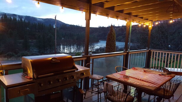 A covered outdoor area with a grill, table, chairs, and a view of a forested valley and river. - Welcome to Lenore Lodge, located along the wild & scenic Clearwater River. (Lenore)