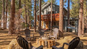 A cabin with a wooden deck, surrounded by tall pine trees. - Family friendly retreat, private forested acreage (Big Bear Lake)