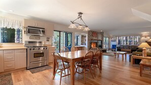 A spacious kitchen with modern appliances, a dining area with wooden furniture, and a cozy living room with a fireplace. - Family friendly retreat, private forested acreage (Big Bear Lake)