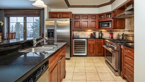 A modern kitchen with wooden cabinets, stainless steel appliances, and a large island with a sink.