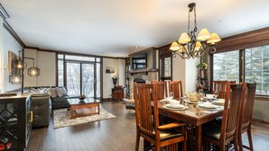 A dining area with a wooden table set for four, surrounded by wooden chairs.