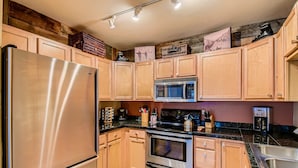 Une cuisine moderne avec des meubles en bois, des appareils en acier inoxydable et un plan de travail en granit.