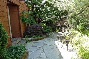 A stone pathway leading to a wooden door, surrounded by lush greenery and white flowering trees. - Walking neighborhood minutes from downtown (Seattle)