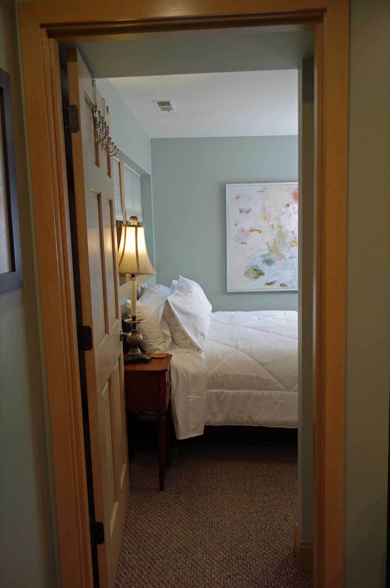 A hotel room with a bed, a nightstand, a lamp, and a painting on the wall.